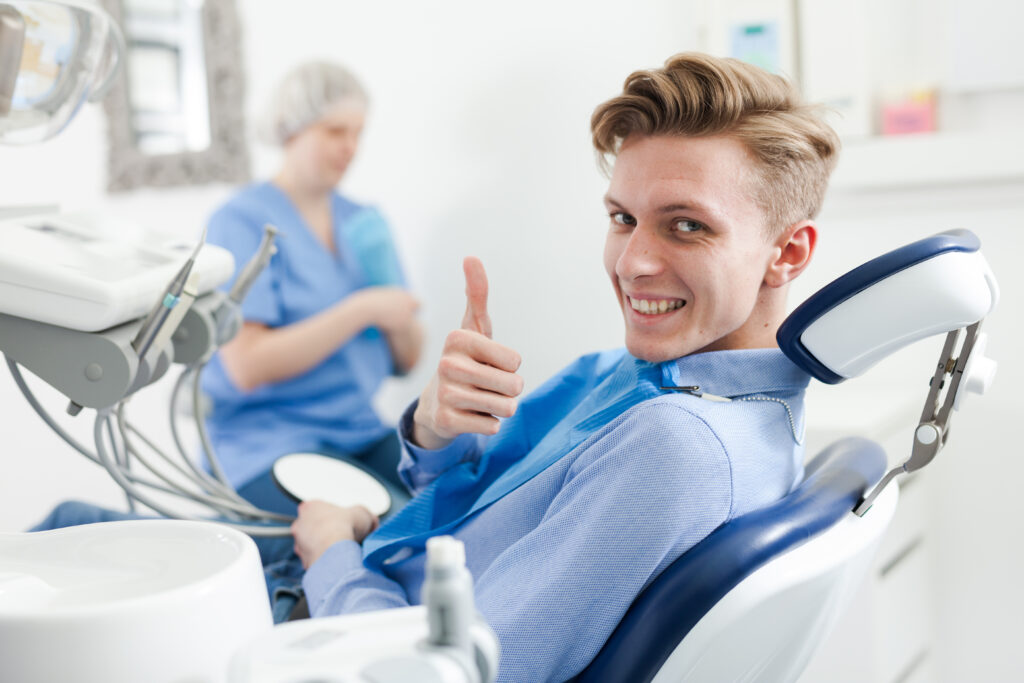 Portrait of satisfied man visiting dentist giving thumbs up in the dental clinic. High quality photo
